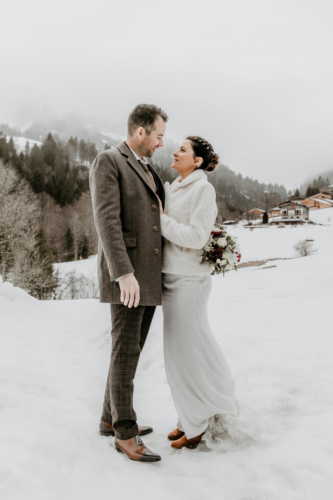 couple de mariés homme et femme dans la neige, femme qui porte des bottes brunes