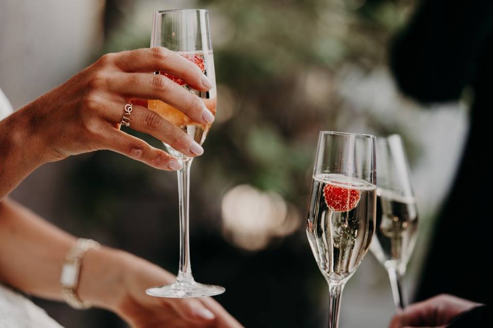 coupe de champagne avec framboise à l'interieur tenue par la main de la mariée