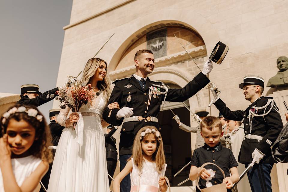 Mariée et son époux en uniforme à la sortie de l'église