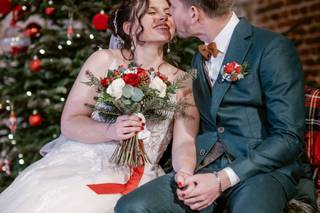 couple devant un sapin rouge et vert assorti au bouquet de la mariée