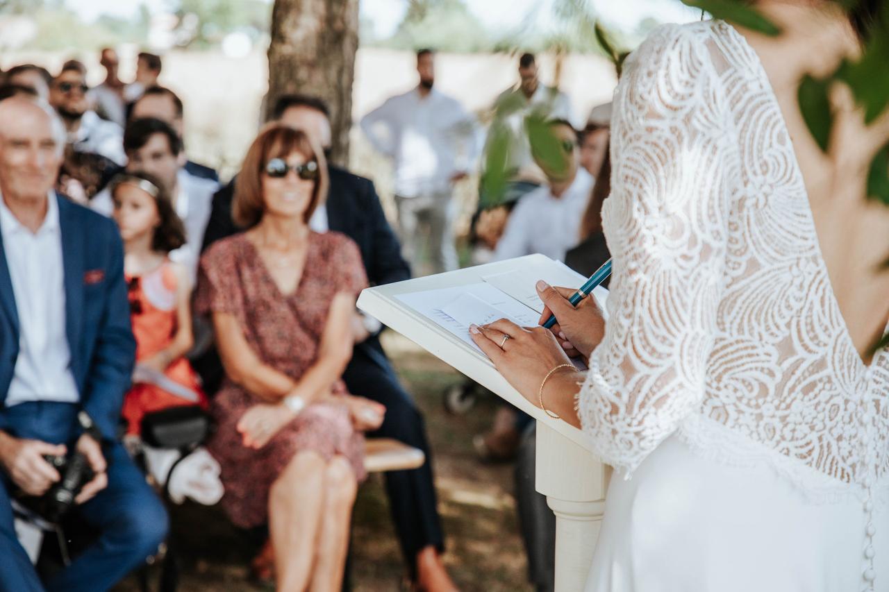 mariée en robe blanche de dos en train de faire son discours face aux invités