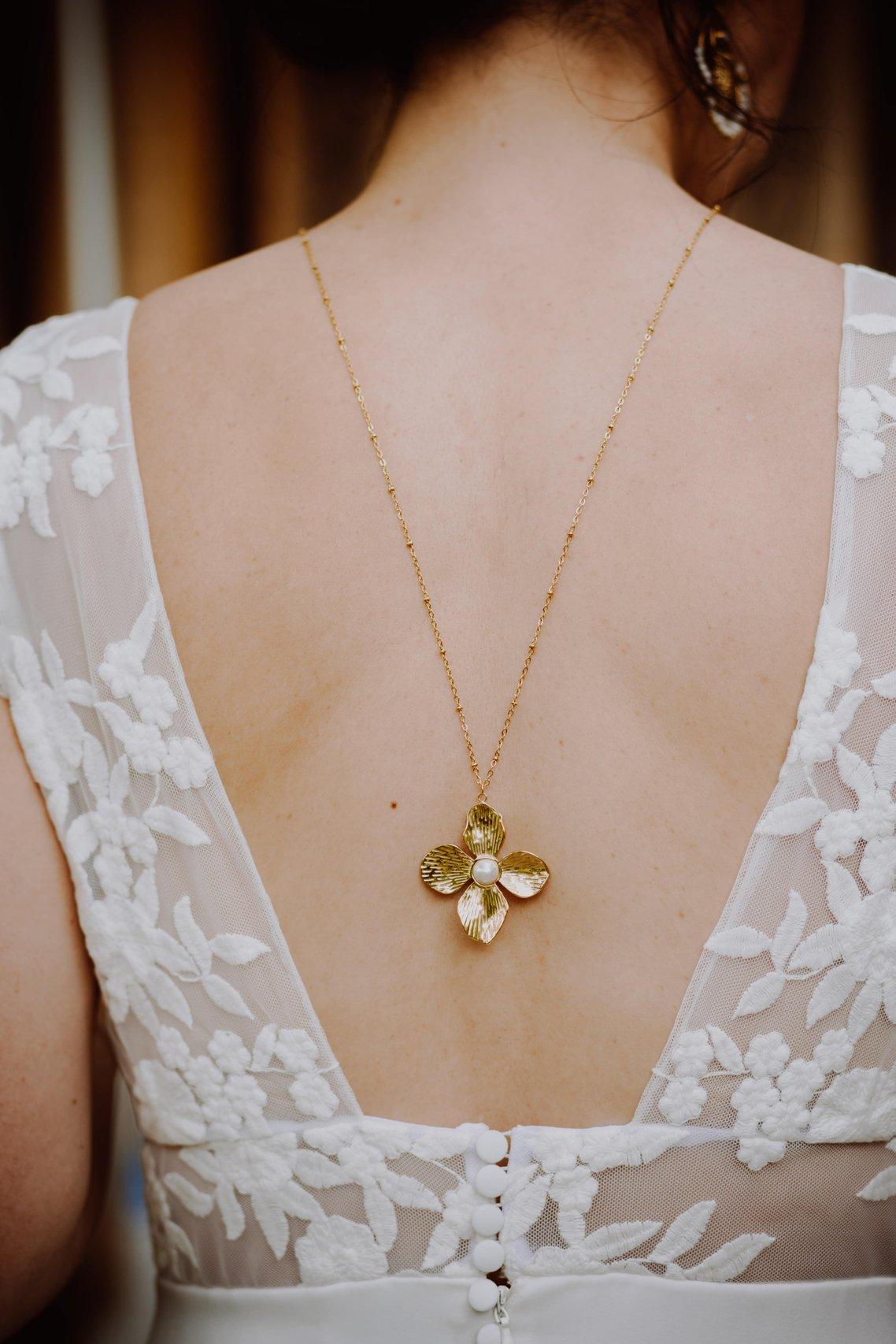 femme en robe blanche portant un collier de dos doré