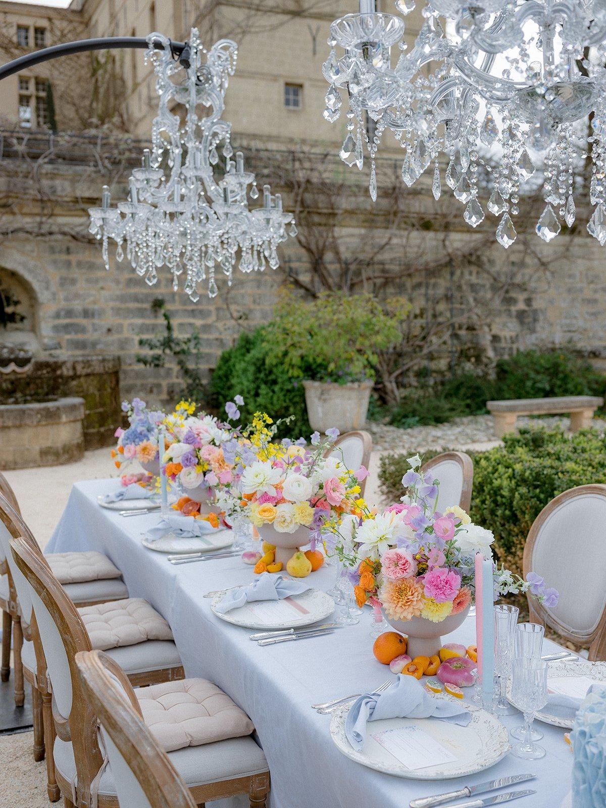 mariage theme bridgerton, style regencycore, table mariage exterieure avec lustres en diamants et fleurs colorées