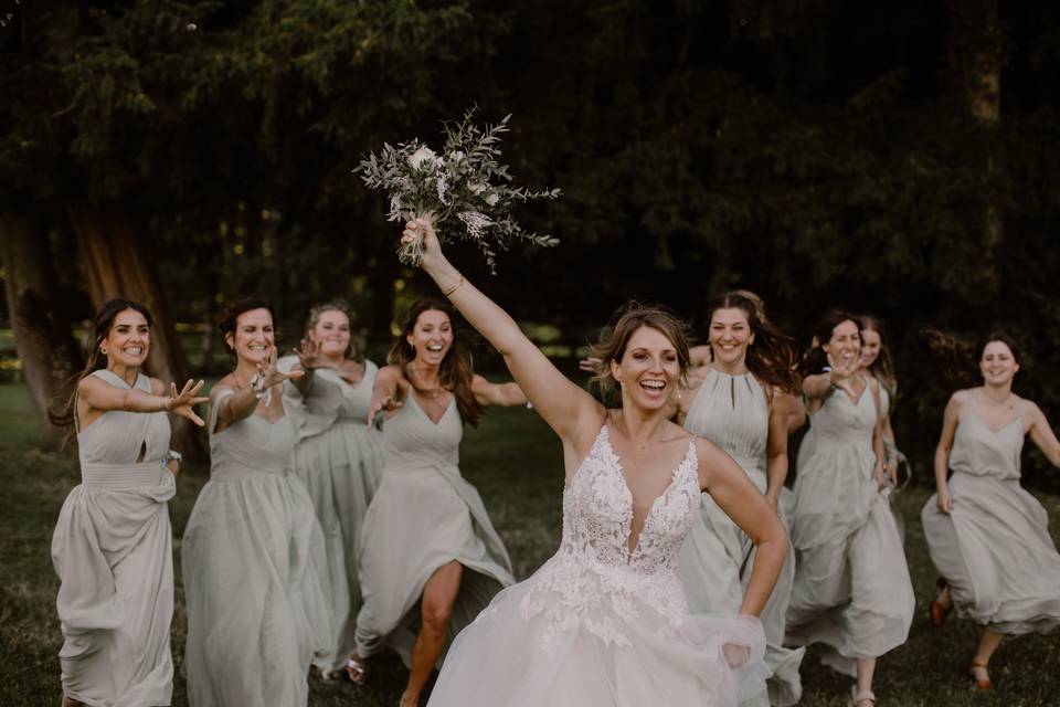 Mariée qui court avec bouquet dans la main et demoiselles d'honneurs