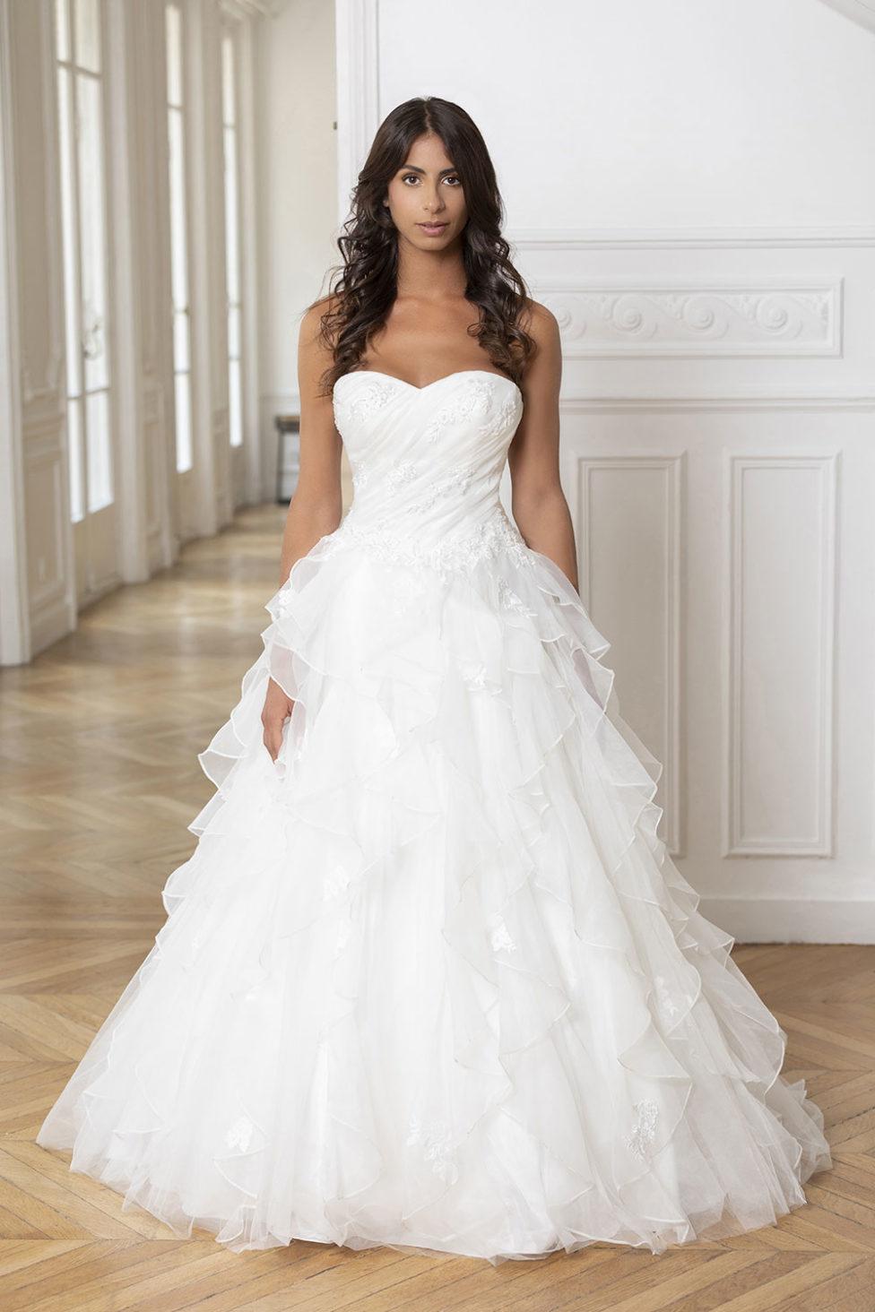 future mariée brune qui porte une robe de mariée blanche bustier coupe princesse, jupe en tulle, location robe de mariée sur paris