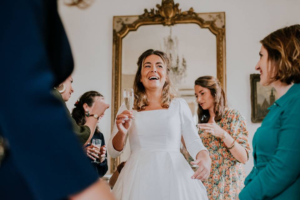 Mariée entourée des proches avec une coupe de champagne à la main