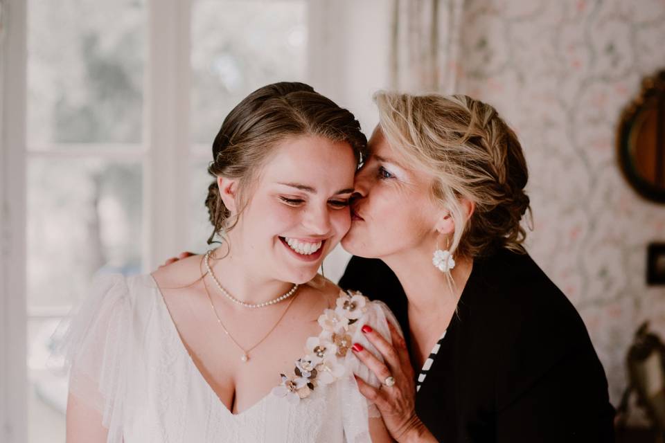 La maman de la mariée qui embrasse sa fille sur la joue pendant les préparations du mariage