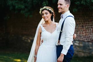 Mariés thème champêtre la mariée porte une robe blanche sans manche avec une couronne de fleurs et le marié un costume bleu et des bretelles