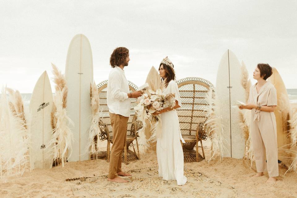 Cérémonie laïque à la plage la mariée porte une robe droite et un diadème et le marié un pantalon beige avec chemise