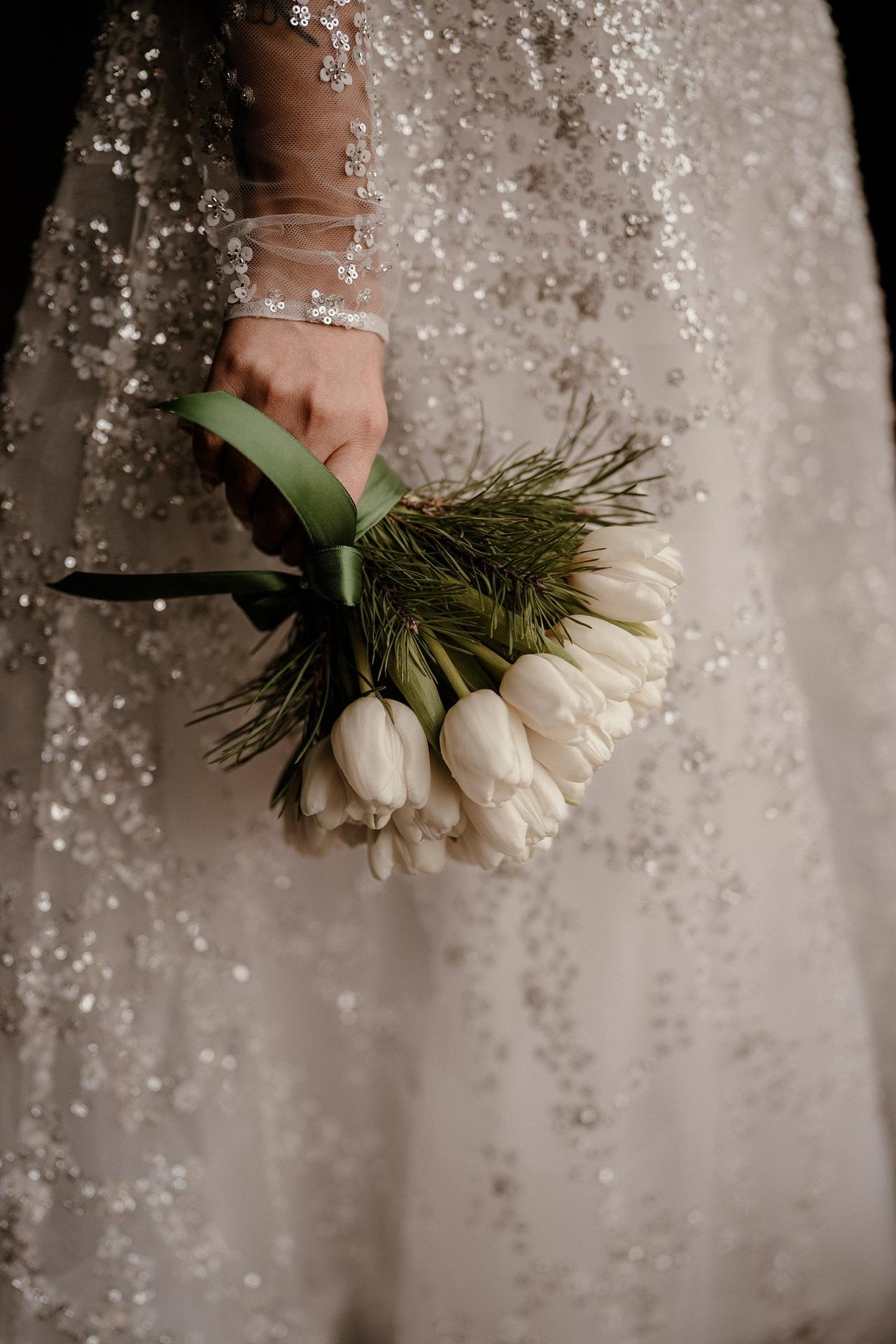 mariée qui tient son bouquet de tulipes blanches à main, fleurs les moins chères pour un mariage les tulipes