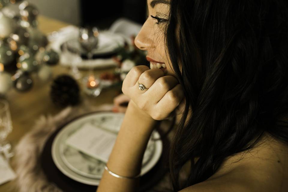 jeune femme brune qui porte une bague de fiançailles à la main gauche, période de noel car un sapin avec boules apparait en fond derrière la jeune fille, demande mariage noel