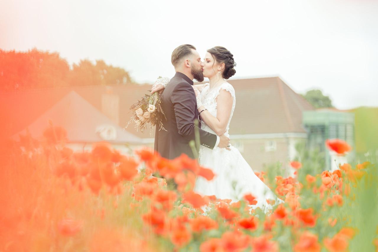 Mariés qui s'embrasse dans un champs de coquelicot