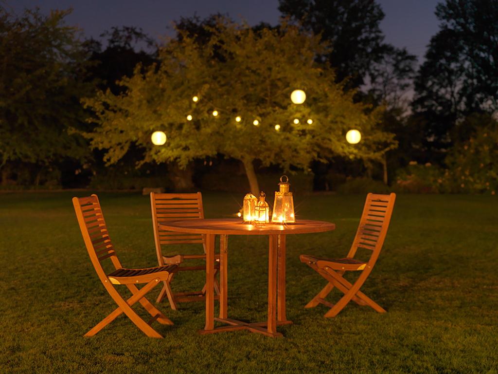 lumière mariage avec bougie sur la table et lampes en papier dans l'arbre