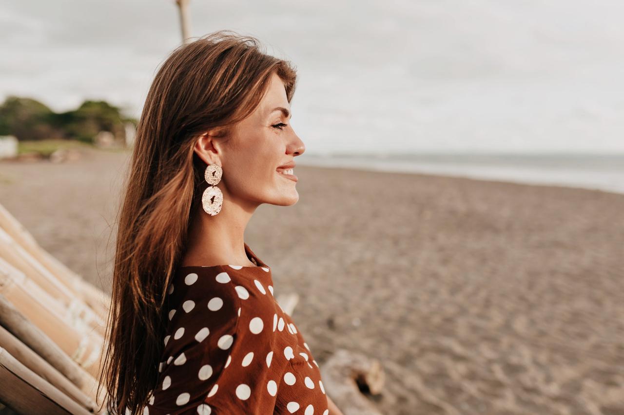 Belle dame avec un sourire doux qui porte des boucles d'oreilles statement