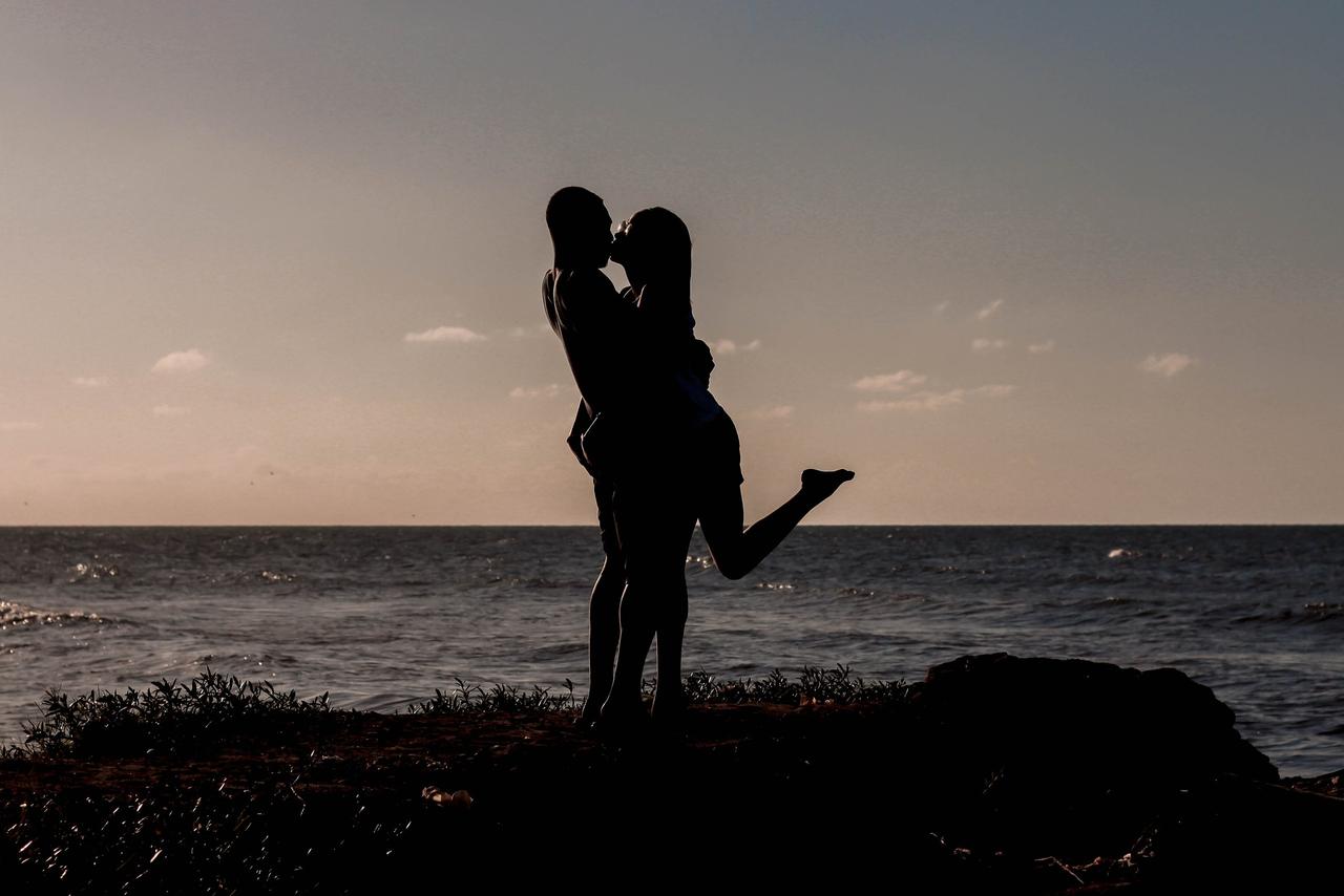 couple au couché du soleil près de la mer qui s'enlace et s'embrasse