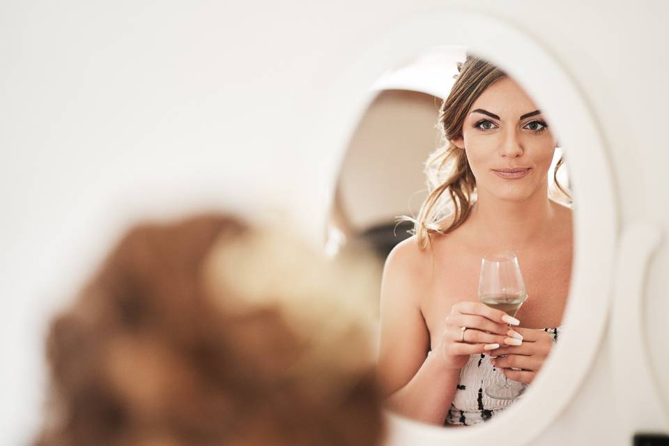 Jeune femme qui se regarde dans le miroir avec une coupe de champage entre les mains