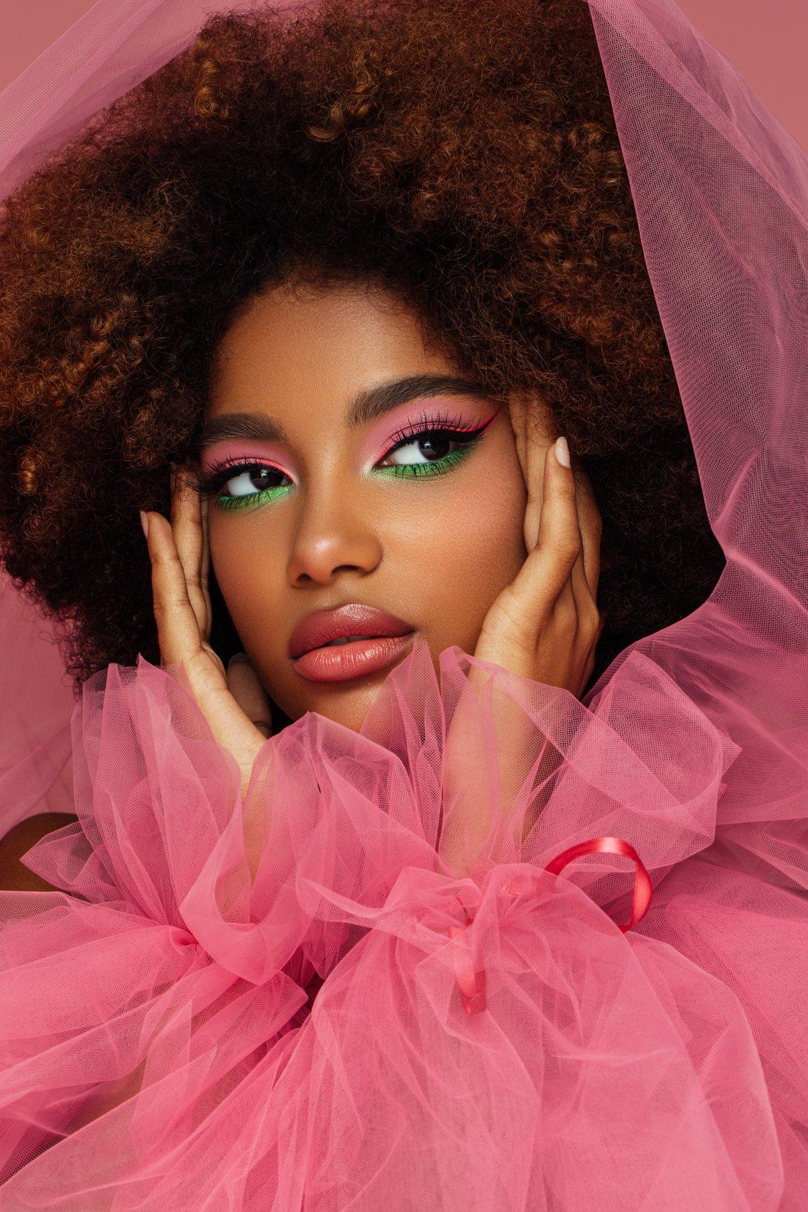 belle femme afro avec un maquillage lumineux rose et vert