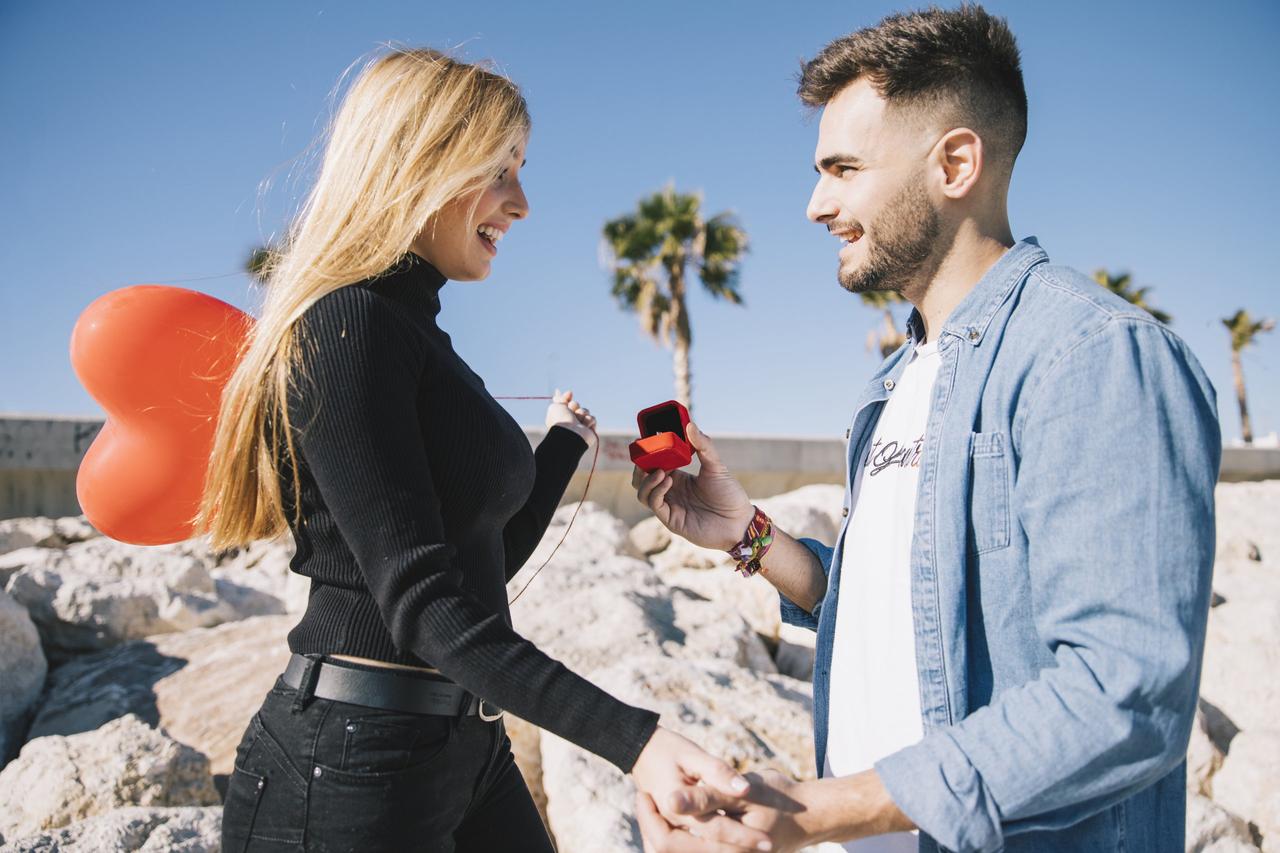 demande en mariage surprise en bord de mer, jeune homme fait sa demande en mariage a sa copine avec une boite a bague de fiançaille