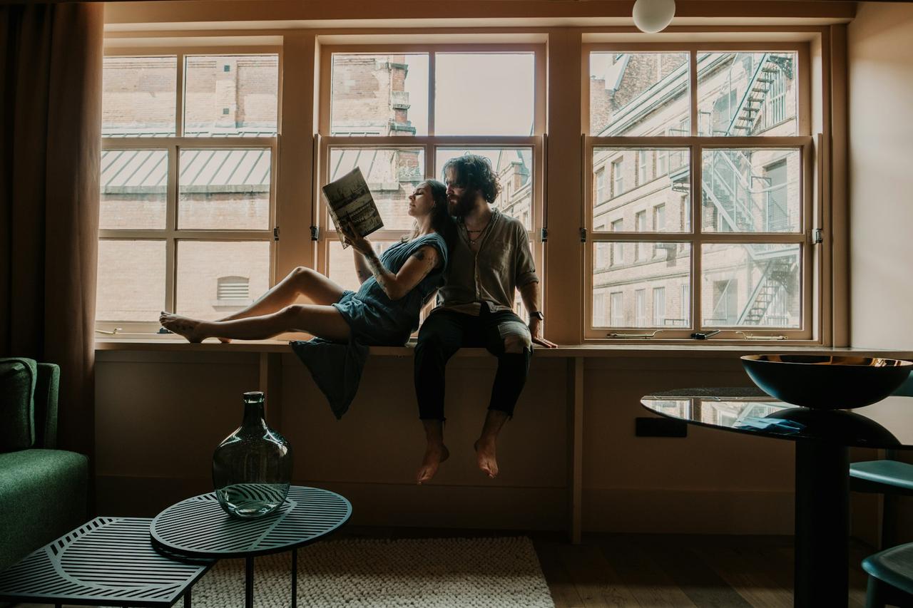 femme assise sur une table en bois marron en train de lire un livre, appuyée sur un homme à ses cotés, livres à lire en couple cet été