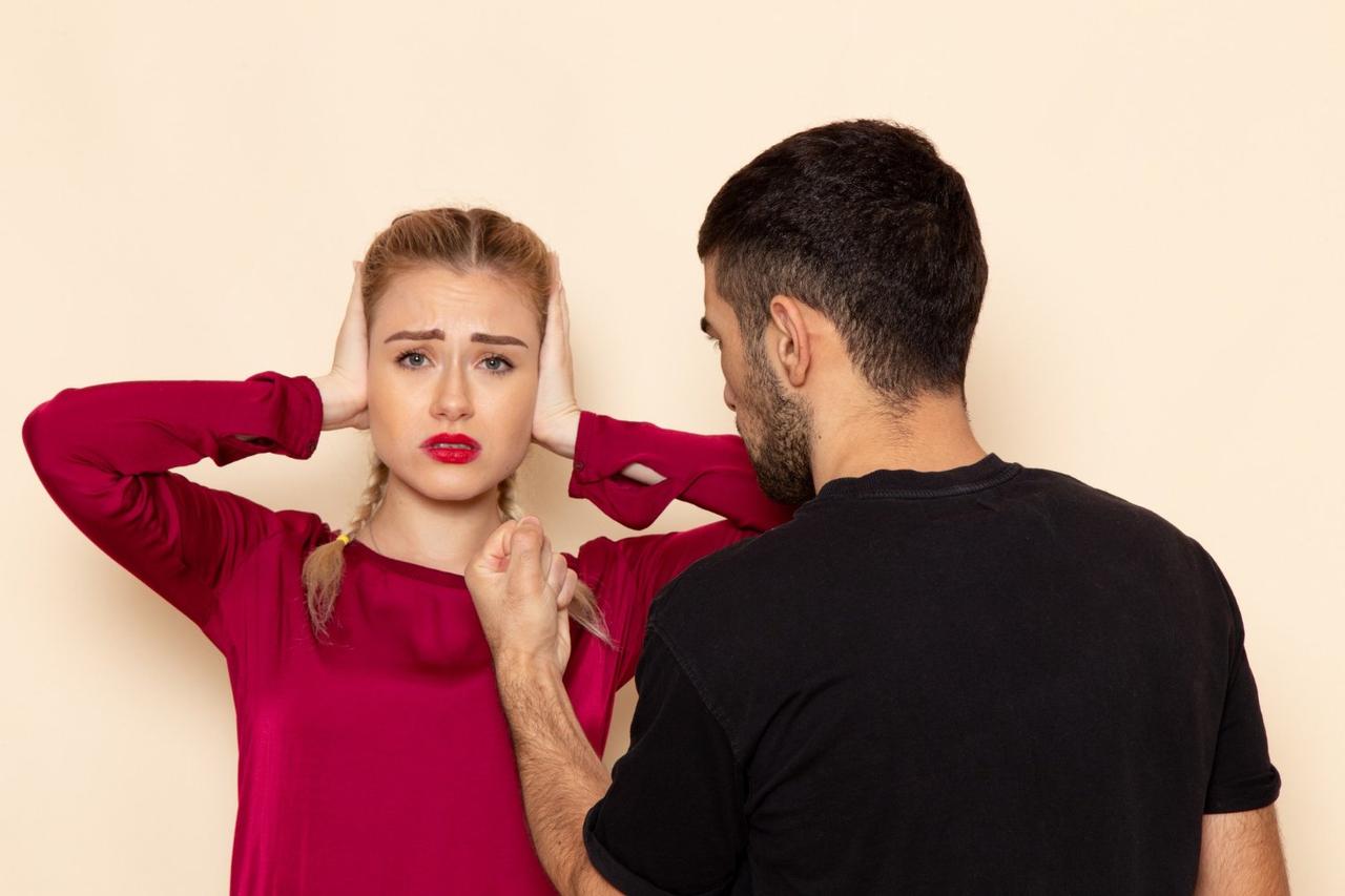 Vue de face jeune femme en chemise rouge souffre de menaces physiques et verbales, phrases préférées des manipulateurs, violence psychologique couple