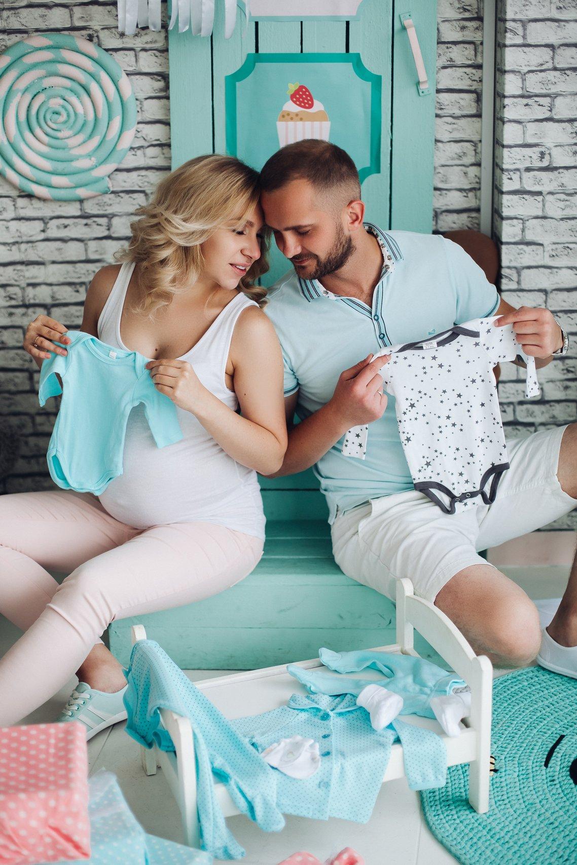 couple de futurs parents qui déballent les cadeaux de la baby shower, vetements pour bébé