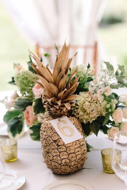 Sur les tables : un ananas doré en centre de table avec le nom de la table et le menu