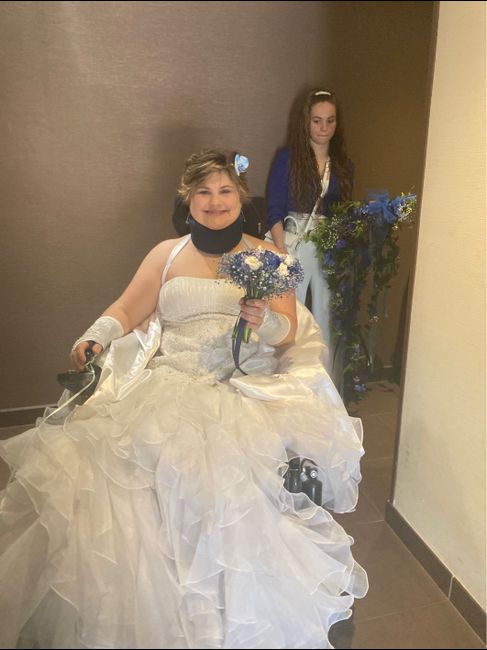 La future mariée avec son bouquet et sa petite sœur qui tient les décorations pour le fauteuil roula