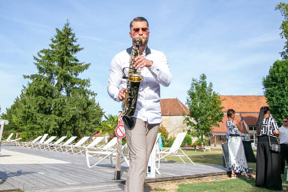 saxophoniste devant haie