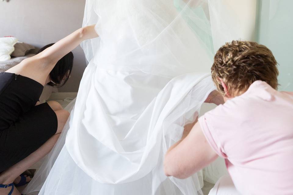 Mariée aidée par sa mère pour enfiler la robe