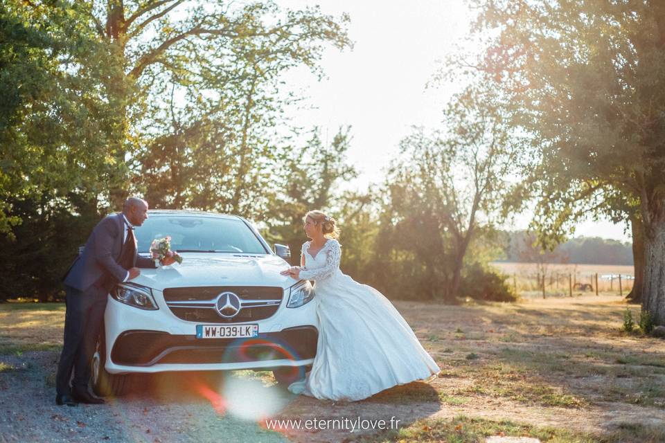 Mariés posant devant la voiture de mariage