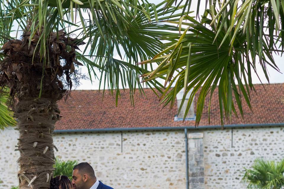 Mariés enlacés près d'un mur en pierre